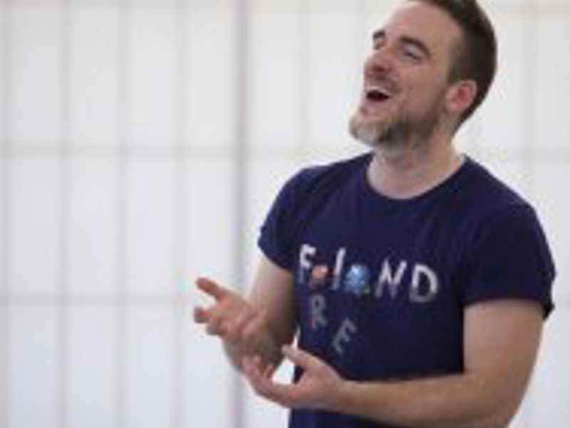 Headshot of Tim Casson. White male with beard laughing wearing blue top