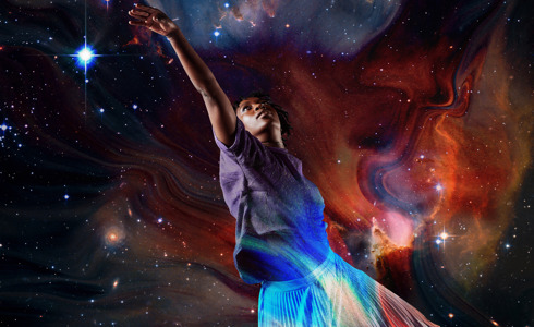 Global majority female dancer reaching to the top left on the image with a superimposed background of the galaxy 