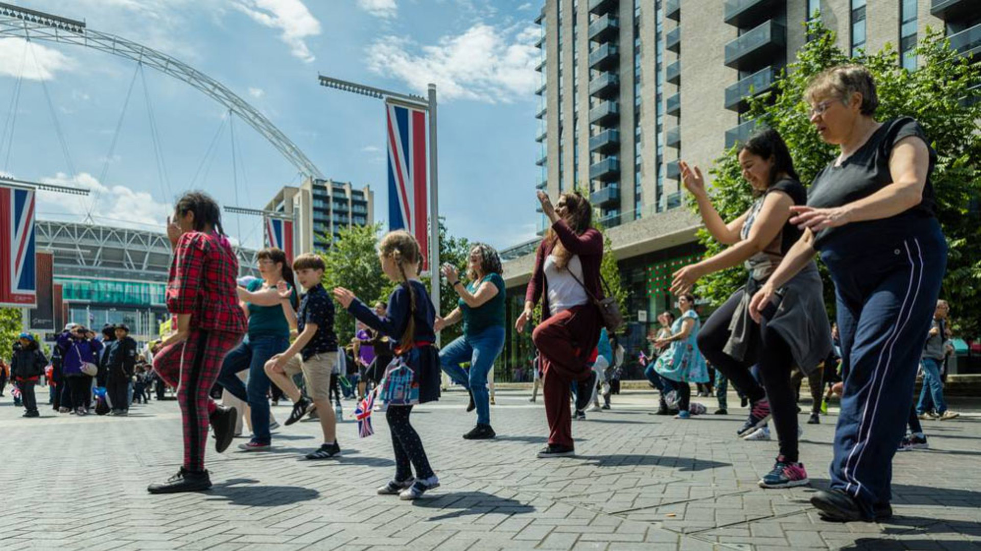 children and adults dancing in the street with large union jack flags 