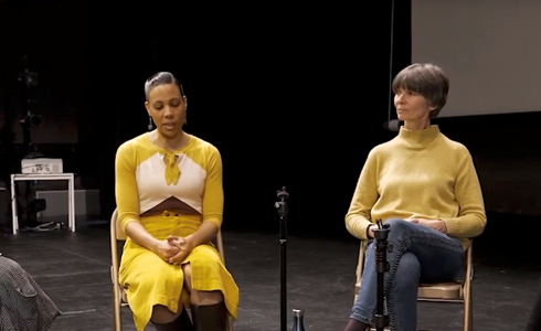 Four females sitting on stage with a microphone on a disscussion panel 