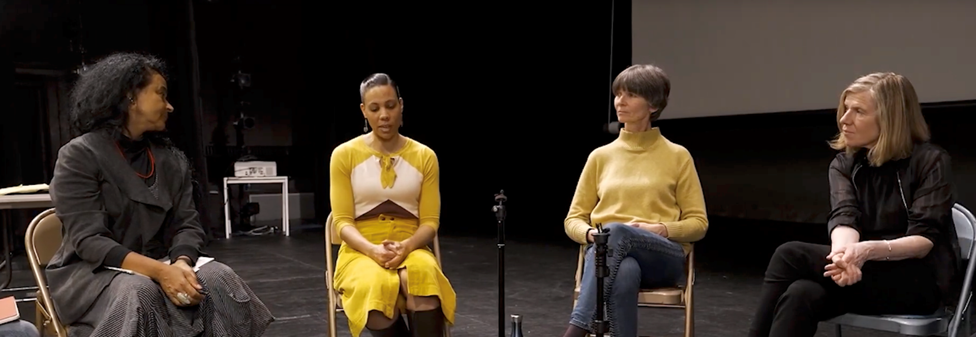 Four females sitting on stage with a microphone on a disscussion panel 