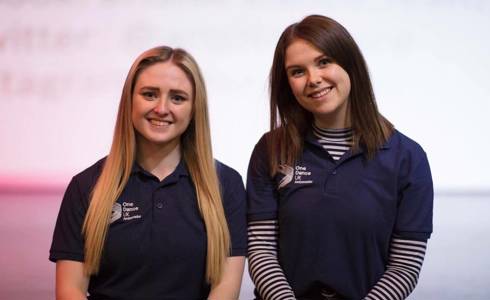 Two female One Dance UK dance ambassadors in blue t-shirts smiling at the camera