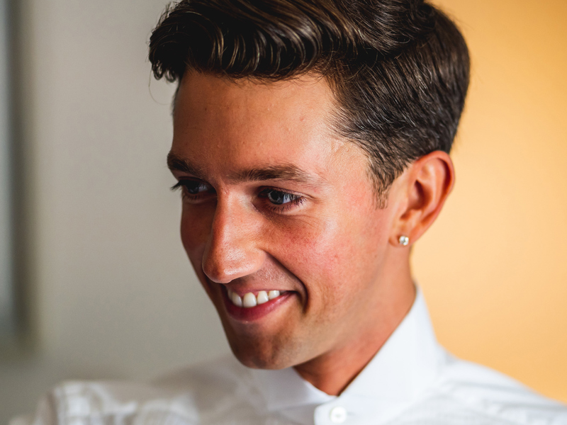 Headshot of Sonny Adam. White male looking down wearing white shirt in front of yellow background