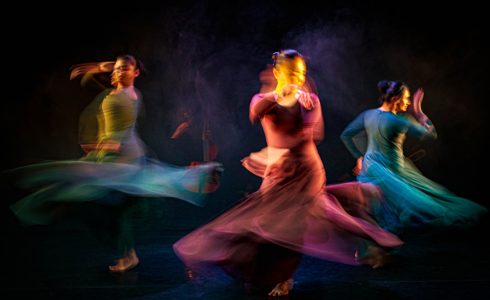 Three female south asian dancers spinning in dresses with motion blur