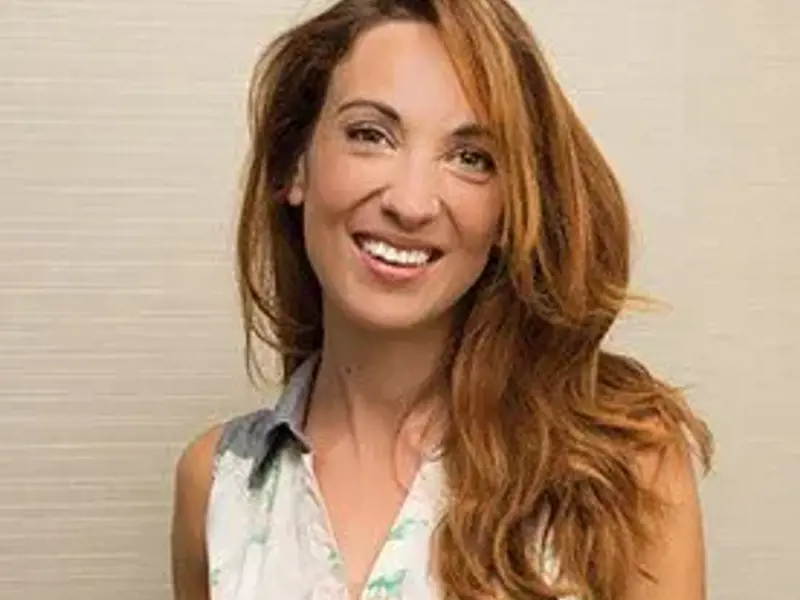 Headshot of Laura Colomban. Female smiling at the camera with long reddish blonde hair. Wearing white shirt.