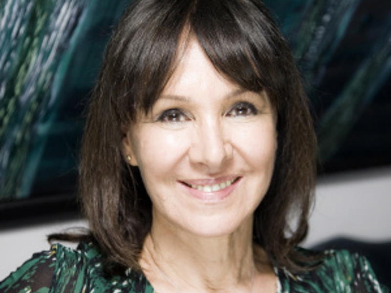 Headshot of Dame Arlene Phillips. White female with short dark hair smiling at the camera wearing green top